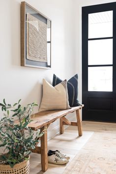 a wooden bench sitting in front of a black door next to a potted plant