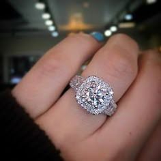 a close up of a person's hand with a diamond ring on their finger