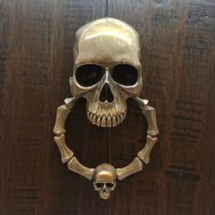 a metal skull mounted to the side of a wooden door with a ring around it