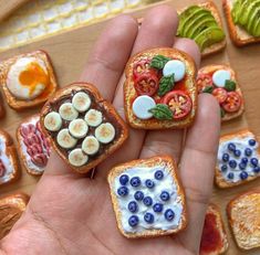 miniature sandwiches with fruits and vegetables on them are being held by someone's hand