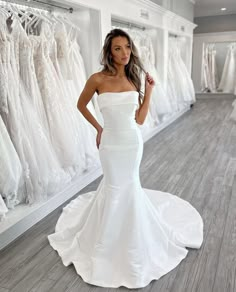 a woman standing in front of a rack of wedding dresses