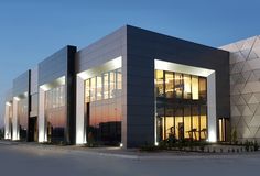 an office building lit up at night with lights on the front and side of it