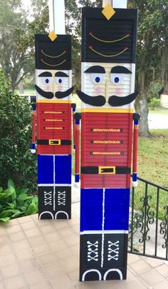 two wooden nutcrackers are standing next to each other in front of a gate