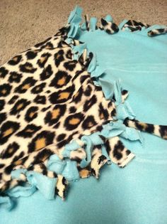 a leopard print blanket laying on the floor next to a blue sheet with black and white spots