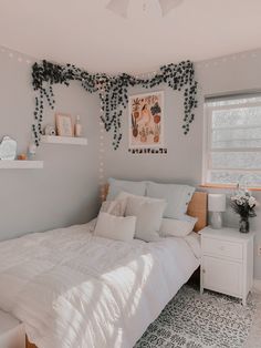 a white bed sitting in a bedroom next to a window with green vines on it