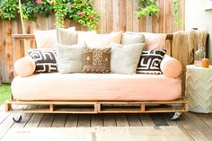 a couch made out of wooden pallets with pillows on it and the words click here