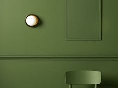 a green room with a white chair and a round light on the wall next to it