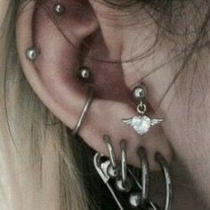 a woman with piercings on her ear and behind her ear is a pair of earrings