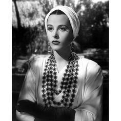 a woman in a white top and black gloves with her arms crossed looking at the camera