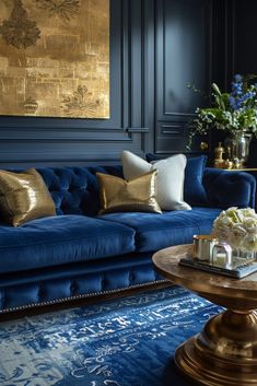 a living room with blue velvet couches and gold pillows on the coffee table in front of it