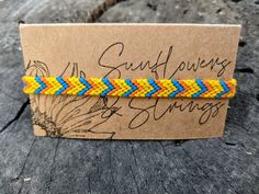 a yellow and blue braided bracelet sitting on top of a piece of wood