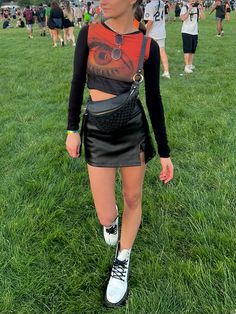 girl at concert festival wearing a graphic long sleeve and leather skirt Skort Concert Outfit, Festival Doc Martens Outfit, Club Outfits With Doc Martens, Doc Martens Rave Outfit, Mesh Top Outfit Summer, Doc Martens Outfit Festival, Mesh Concert Outfit, Doc Martens Concert Outfit, Cut Out Top Outfit