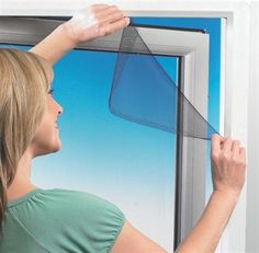 a woman is looking out the window with her hand on the glass and holding onto the screen