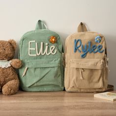 two backpacks and a teddy bear are sitting on the floor next to each other