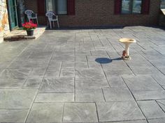 an empty patio with two chairs and a table on the ground in front of a brick building