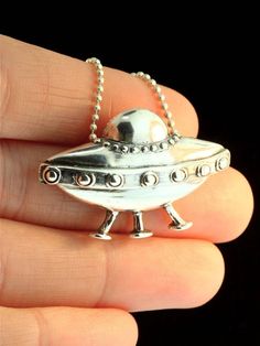 "This solid sterling silver U.F.O pendant is totally out of this world! This three legged saucer is carefully detailed with 7 portholes, rivets and a control dome. It is 1\" high and 1 1/2\" across and ready for take off. This item usually ships the same or next business day. All Marty Magic Jewelry is packaged in a beautiful purple box, embossed with the gold foil Marty Magic dragon logo. Perfect for any occasion! Designed in Santa Cruz, California by Marty Magic. Made in the U.S.A." Flying Saucer Necklace, Space-themed Sterling Silver Jewelry Gift, Silver Space-themed Jewelry Gift, Space-themed Silver Round Pendant Necklace, Spaceship Necklace, Alien Jewelry, Cosmic Necklace, Sci Fi Jewelry, Ufo Jewelry