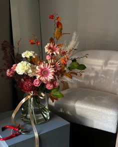 a vase filled with flowers sitting on top of a blue table next to a white couch