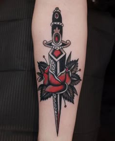 a tattoo on the arm of a person with a dagger and rose in its center