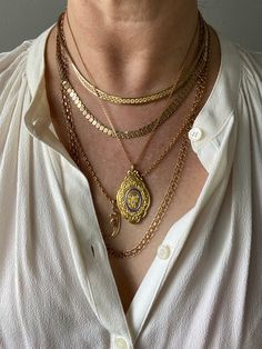 a woman wearing three different necklaces on her chest and one has a gold medallion