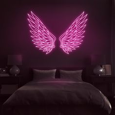 a bed in a room with a neon angel wings wall decal on the wall