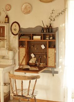 an old fashioned desk and chair in the corner of a room with plates on the wall