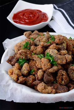 a white bowl filled with meatballs and ketchup on top of a table