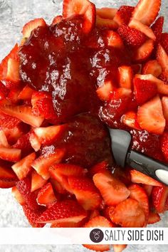 a bowl filled with sliced strawberries next to a knife