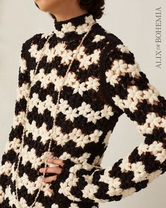 a woman wearing a black and white crochet sweater with flowers on the sleeves