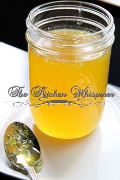 a glass jar filled with liquid sitting on top of a white plate next to a spoon