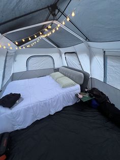 the inside of a tent with a bed in it and lights strung from the ceiling