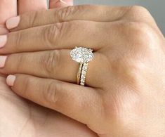 a woman's hand holding a ring with a diamond on it and the other hand