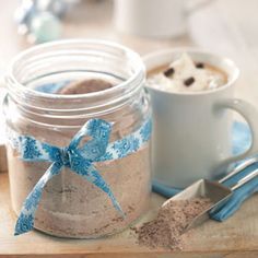 a cup of coffee and spoons on a table with some cookies in the jar