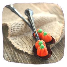 two small pumpkins sitting on top of a wooden table next to silver spoons