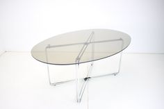 an oval glass table with metal legs on a white floor