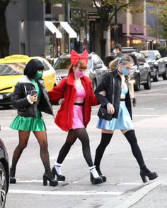 three women in costumes crossing the street