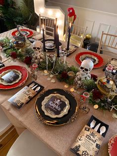 a table set for halloween dinner with skulls, candles and other holiday decorations on it