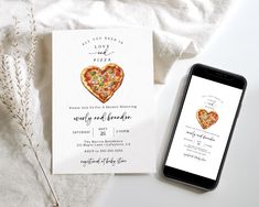 a card with a heart shaped pizza on it next to an iphone and some flowers