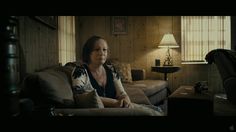 a woman sitting on top of a couch in a living room next to a lamp