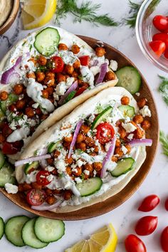 two tacos on a plate with cucumbers, tomatoes, and other vegetables