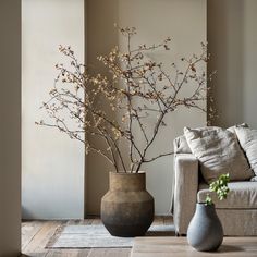 two vases with flowers in them sitting on the floor next to a couch and table