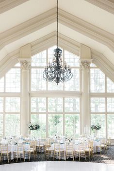 a large room filled with lots of tables covered in white linens and chandeliers