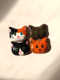 three ceramic cats sitting next to each other on top of a white surface with one cat looking at the camera