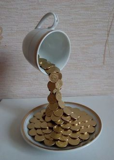 a white cup filled with gold coins on top of a plate