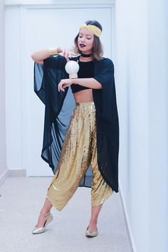 a woman in gold sequins is holding a white object and wearing a black top