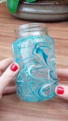 a woman's hand holding a blue glass jar