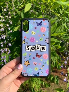 someone is holding up their phone case with the word squir on it in front of some flowers