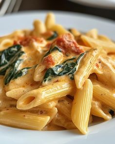 a white plate topped with pasta and spinach