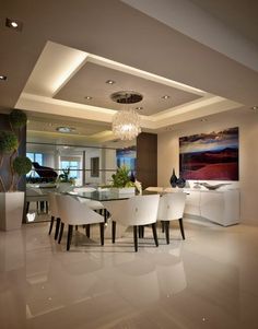 a modern dining room with white chairs and a large painting on the wall behind it