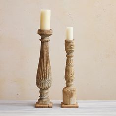 two wooden candlesticks sitting next to each other on top of a white table