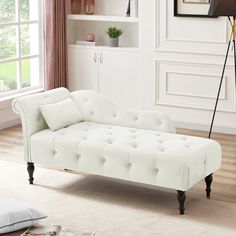 a white couch sitting on top of a wooden floor next to a book shelf filled with books